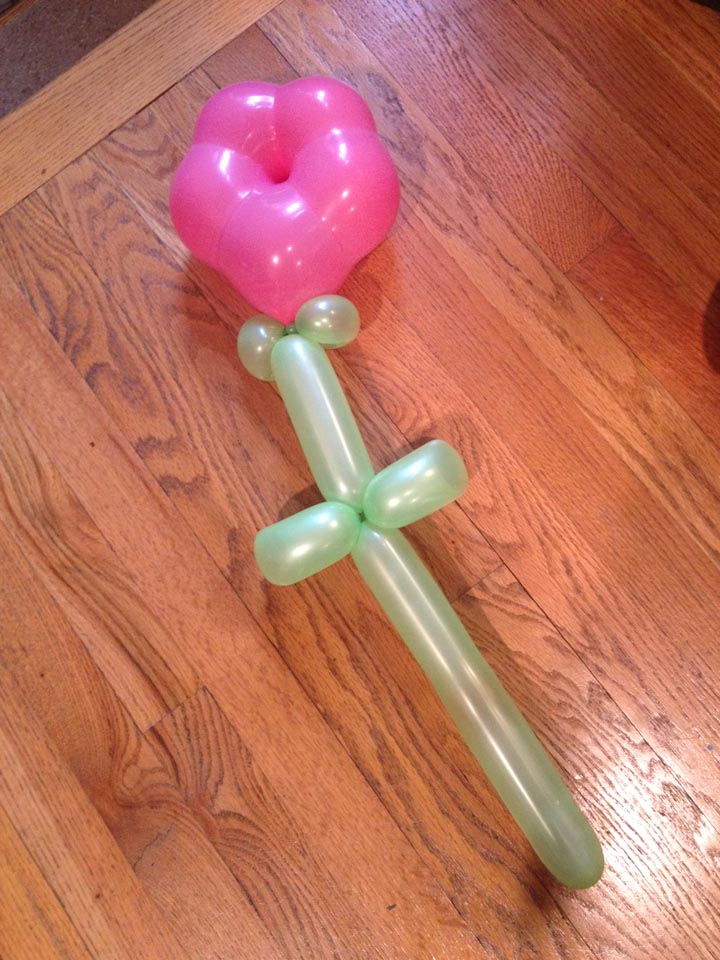 A balloon sculpture depicting a pink rose with a green stem