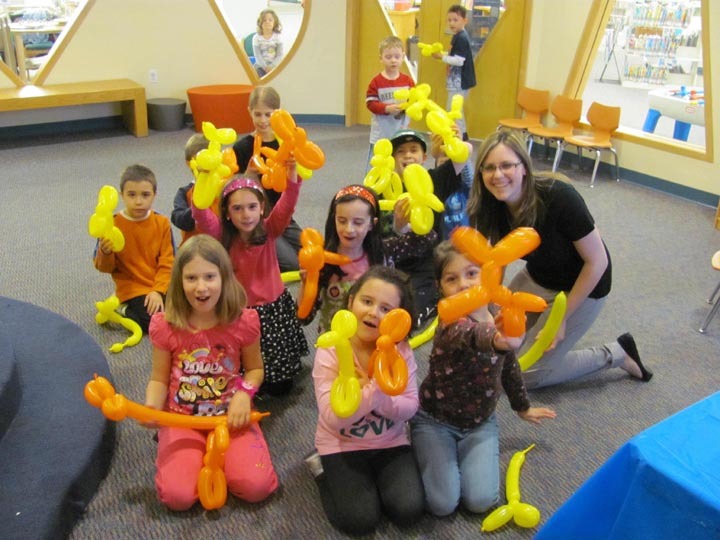 Children and an instructor celebrate a balloon animal-making session