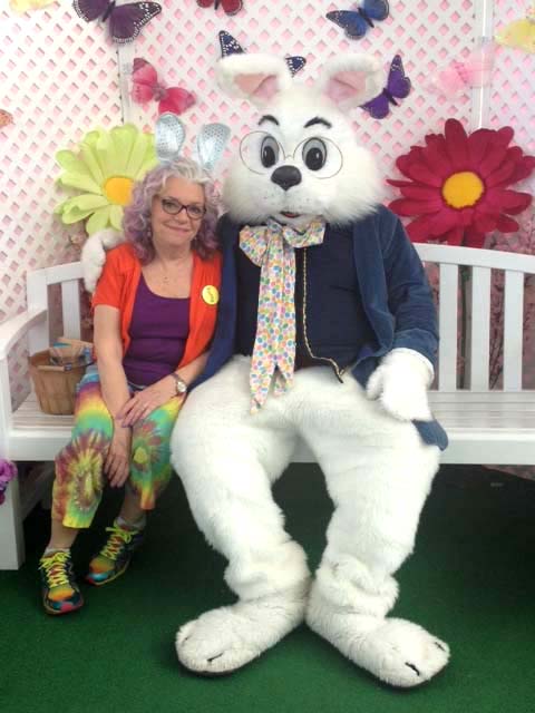 A woman with lavender hair poses beside a large bunny