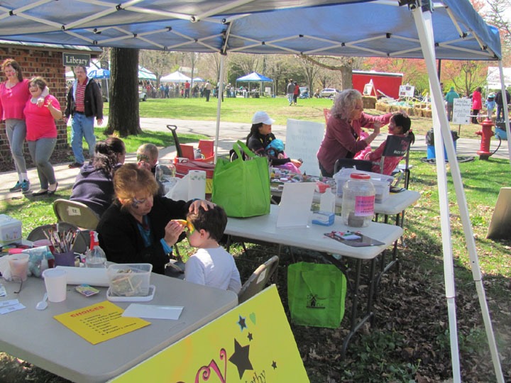 Children receive face painting at a lively outdoor festival