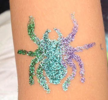 Glittery spider design on a person's forearm,