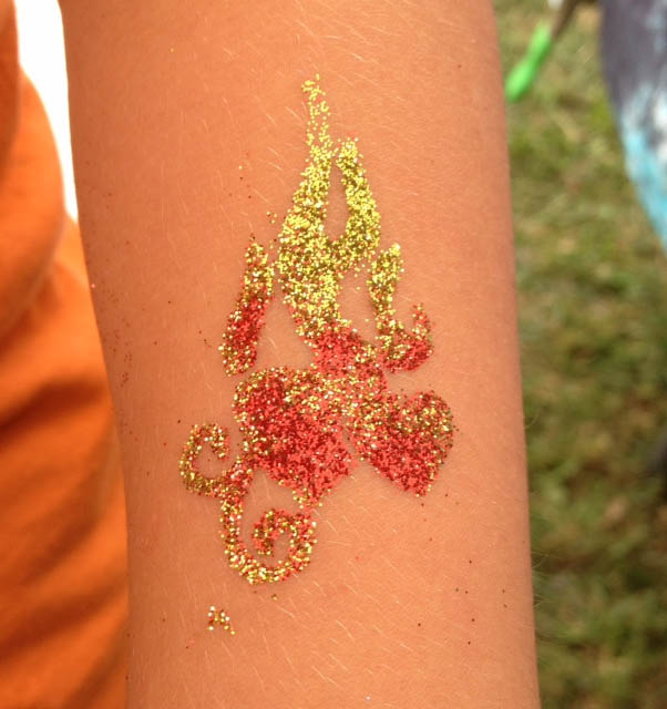 Glitter tattoo featuring red hearts and stylized flames in yellow and red