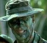 Soldier with camouflaged face paint and a wide-brimmed hat