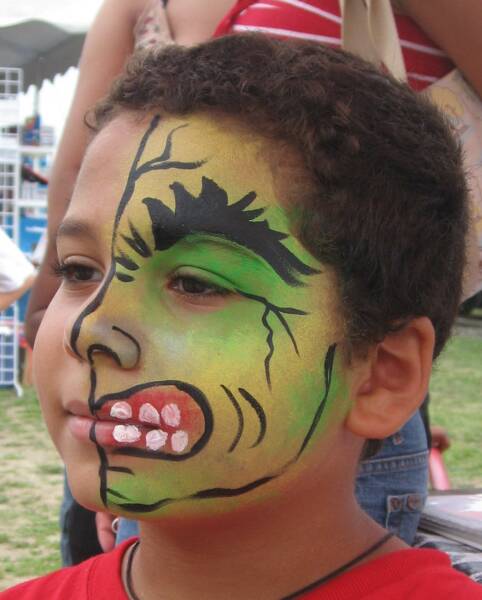 Boy with face paint depicting a green monster,