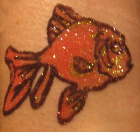 A glittery orange goldfish tattoo on the skin