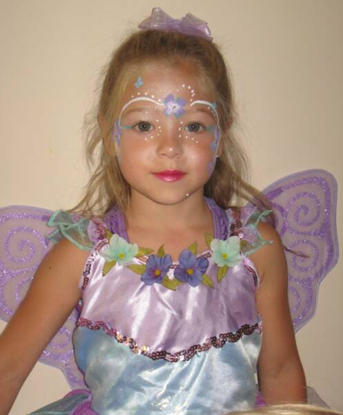 Young girl dressed as a fairy, wearing a purple costume and decorative face paint