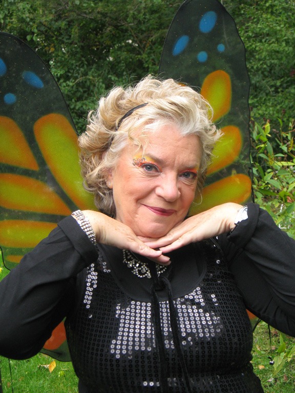 Woman with butterfly wings poses playfully outdoors