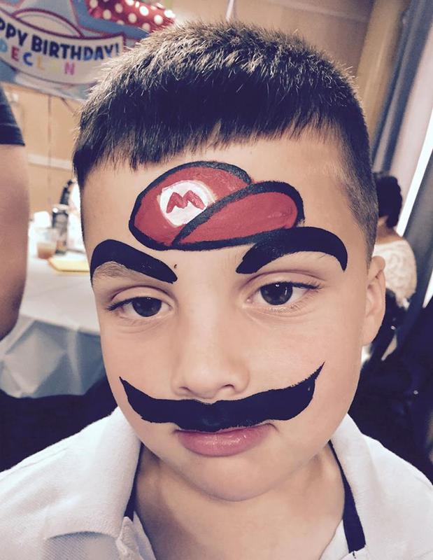 A boy with face paint resembling Mario