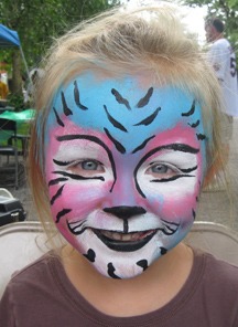 A young girl with face paint resembling a tiger
