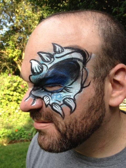 Man with intricate face paint resembling a creature blue and black colors