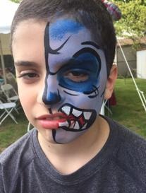 A boy with face paint featuring a half-blue, half-monster design