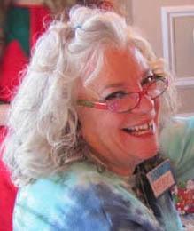 Smiling woman with curly gray hair and colorful glasses