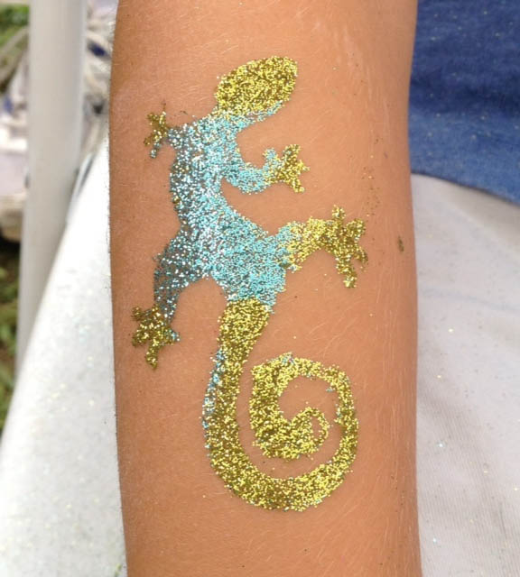 Glittery lizard tattoo in blue and gold adorns a child's forearm